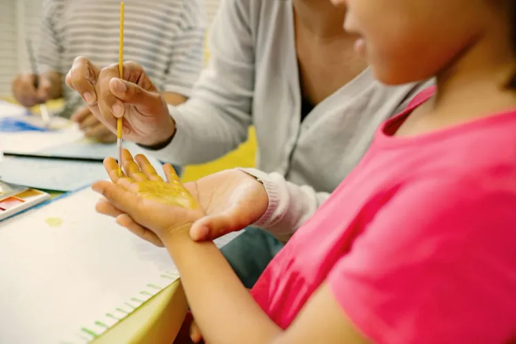 Child hand-painting with golden watercolors