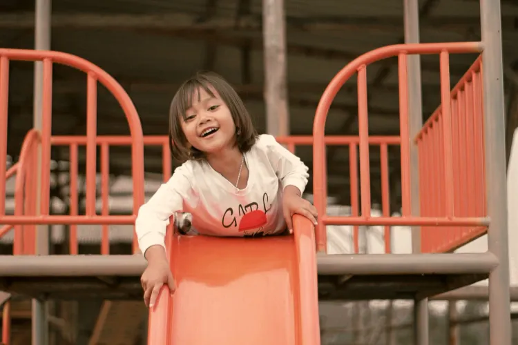 Smiling child playing on a playground slide