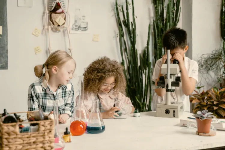 Children exploring science with a microscope and colorful flasks