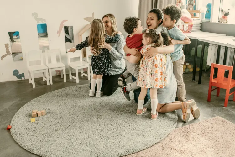 Teachers embracing happy children in a warm classroom